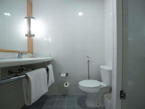 a white bathroom with a toilet and a sink at ibis Caxias do Sul in Caxias do Sul