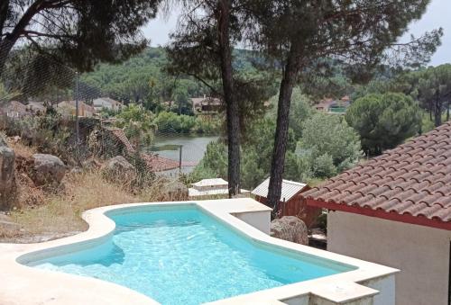 a swimming pool in front of a house and a river at La Senda del Lago PISCINA PRIVADA in Córdoba