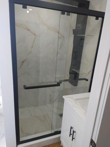 a shower with a glass door in a bathroom at Nigam's Sweet Home in Saint John
