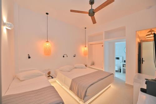 a white bedroom with two beds and a ceiling fan at kleris apartment 3 in Tinos