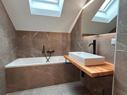 a bathroom with a sink and a tub and skylights at NockLodge Sankt Oswald in Bad Kleinkirchheim