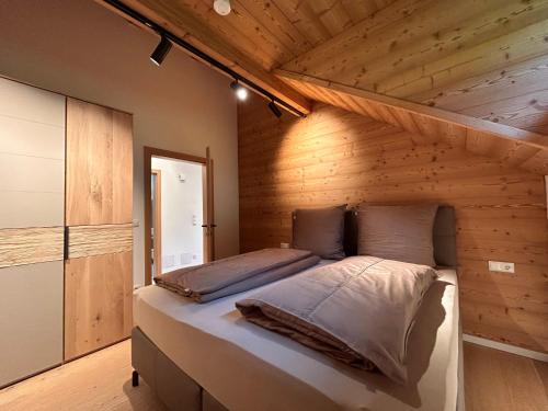 a bedroom with a bed in a wooden room at NockLodge Sankt Oswald in Bad Kleinkirchheim
