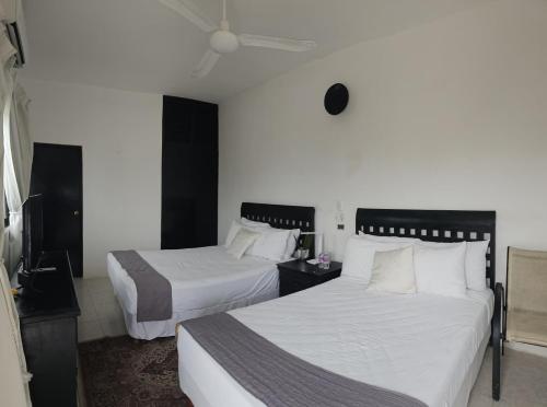 a hotel room with two beds and a tv at Casa del Viento Celestun in Celestún