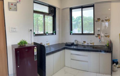 a kitchen with white cabinets and a sink and windows at Auravista in Pālghar