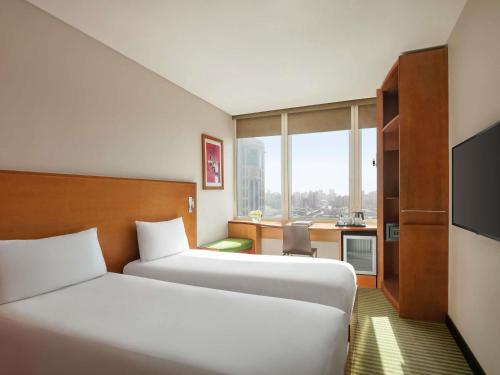 a hotel room with two beds and a desk at ibis Kuwait Salmiya in Kuwait