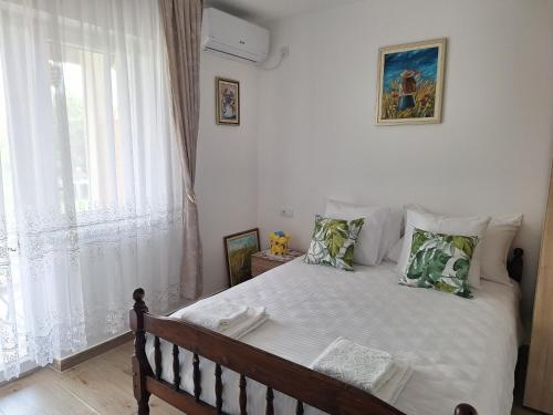 a bedroom with a bed with white curtains and a window at Apartman ISKRA in Mataruška Banja