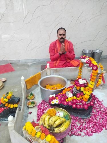 a man sitting on a table with a bunch of flowers at Mauni Ashram in Prayagraj