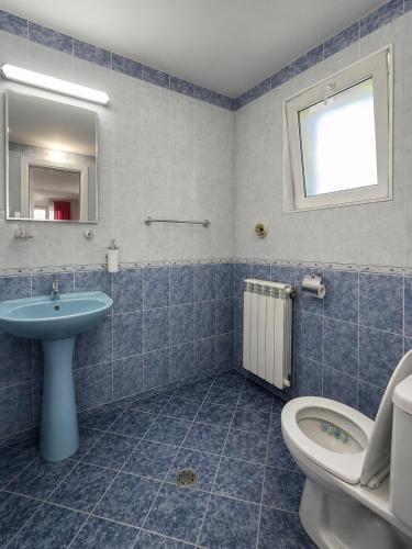 a blue tiled bathroom with a toilet and a sink at Къща за гости "Марина ливада" in Velingrad