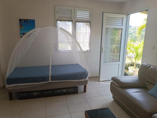 a bed in a living room with a clear canopy at Le petit coin de campagne in Le Robert