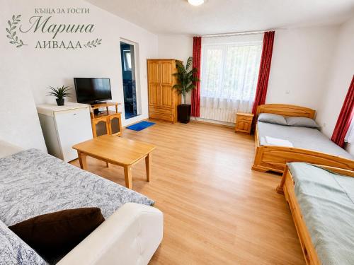 a living room with two beds and a table at Къща за гости "Марина ливада" in Velingrad