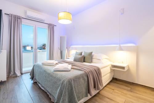 a bedroom with a large bed with a large window at White Rock Milos Suites in Adamantas