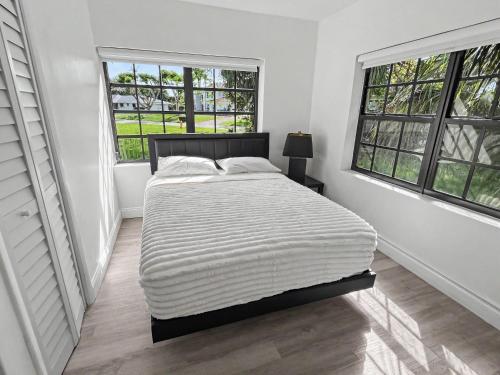 a white bedroom with a bed and two windows at Casa Arya in Howard