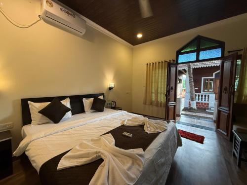 a bedroom with a large bed and a window at Baga Beach Palm Cottage in Calangute
