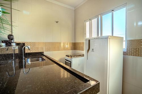 a kitchen with a refrigerator and a sink at Souza Apart 1 - Apartamentos completos com muito aconchego in São Thomé das Letras