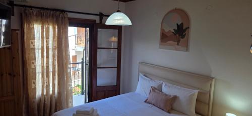a bedroom with a white bed and a window at Zeus Guesthouse in Panagia
