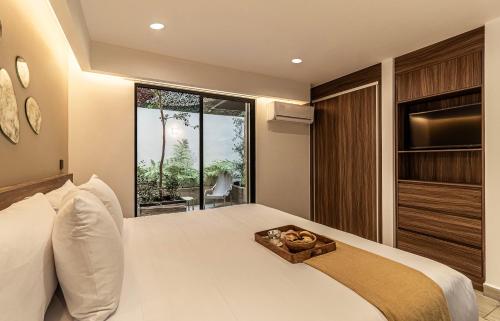 a bedroom with a large white bed and a window at Casa Grijalva by Kukun Apartments in Mexico City