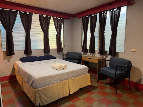 a bedroom with a bed and two chairs and windows at Hostal Harvest House in León
