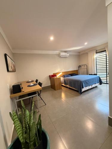 a bedroom with a bed and a table and a desk at Studio Central IV in Cascavel