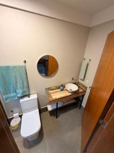 a bathroom with a sink and a toilet and a mirror at Studio Central IV in Cascavel