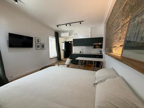 a bedroom with a large bed and a kitchen at Casa Plaza do Millo in Celanova