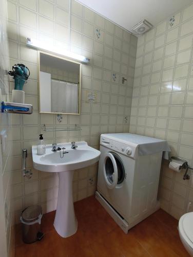 a bathroom with a washing machine and a sink at Apartamentos Xoroi in Cala en Porter