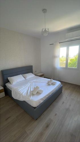 a bedroom with a large bed with white sheets and a window at Mateo Apartaments in Vlorë