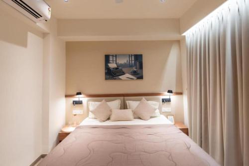 a bedroom with a large white bed with two pillows at Velora Stays - Nr Airport & World trade center in Pune