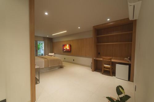 a bedroom with a bed and a desk and a kitchen at Mantra Hotel in Feliz Natal