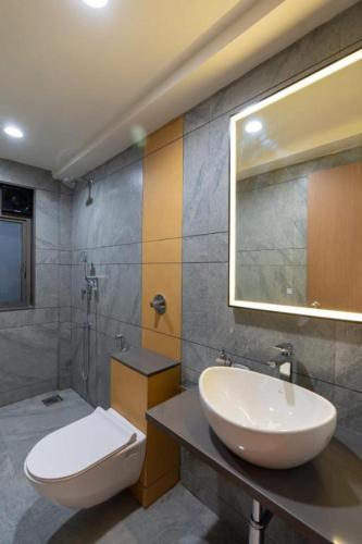 a bathroom with a sink and a toilet and a mirror at Velora Stays - Nr Airport & World trade center in Pune