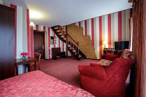 a living room with a red couch and a staircase at Viešbutis "Linelis" in Paplatelė