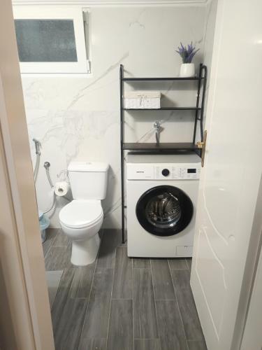 a bathroom with a toilet and a washing machine at Elenis Garden View Apartment in Perea