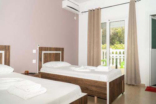 two beds in a room with a window at Joy & Grace Apartments Ksamil in Ksamil