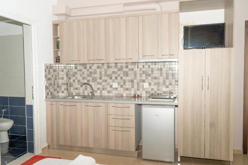 a kitchen with wooden cabinets and a sink at Joy & Grace Apartments Ksamil in Ksamil