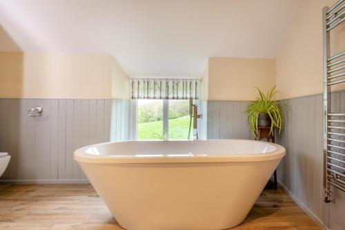 a large white bath tub in a bathroom with a window at 2 Bed in Abergele oc-88974 in Llanfair Talhaiarn