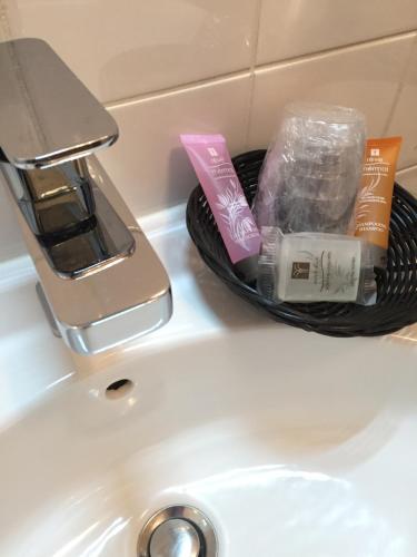 a sink with toothbrushes and other items on it at Hotel l'Avenue in Chantilly