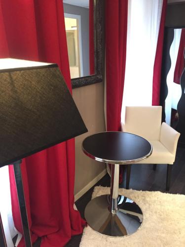 a table and a chair in a room with red curtains at Hotel l'Avenue in Chantilly