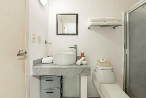 a white bathroom with a sink and a toilet at Beachfront Duplex with Multiple Pools - Beachclub in Nuevo Vallarta