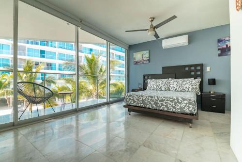 a bedroom with a bed and large windows at Beachfront Duplex with Multiple Pools - Beachclub in Nuevo Vallarta