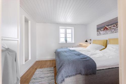 a white bedroom with a bed and a window at Kalvestalden - A Cozy Holiday Home in Hjørring