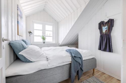 a bedroom with a bed with white sheets and blue pillows at Høloftet - Charming Vacation Apartment On The 1St Floor Of Hawbakken in Hjørring