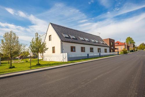 a white house with a black roof on a street at Apartmány Dalov in Šternberk