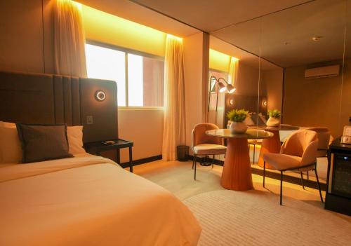 a hotel room with a bed and a table and chairs at Uchôa Teresina Hotel in Teresina