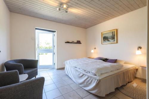 a bedroom with a bed and two chairs in it at Fantastic Holiday Property Kragelund For Up To 24 Guests! in Åbybro