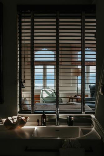 a kitchen sink with a window with a view of the ocean at Strandhotel Ostende Adults Only in Ahlbeck