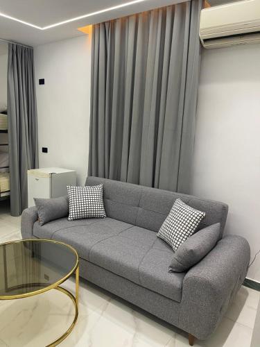 a living room with a gray couch and a glass table at Luxury king studio in 6th Of October