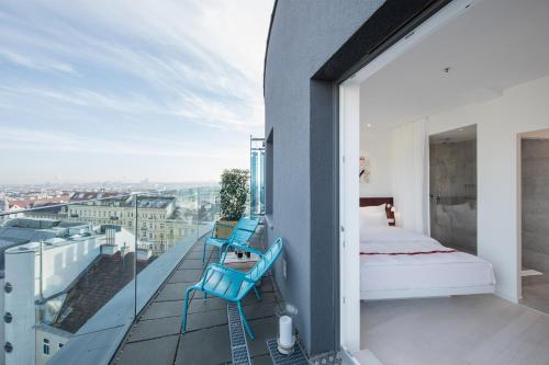 a bedroom with a bed and two chairs on a balcony at Ruby Marie Hotel Vienna by IHG in Vienna