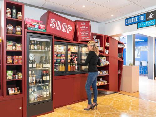 a woman is standing at a store refrigerator at Aparthotel Adagio Val d'Europe près de Disneyland Paris in Serris