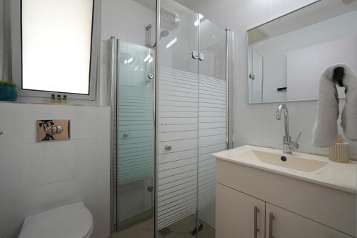a bathroom with a glass shower and a sink at וילה מארי עם בריכה במגדל in Migdal