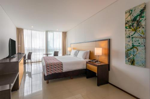 a hotel room with a bed and a flat screen tv at Estelar Alto Prado in Barranquilla