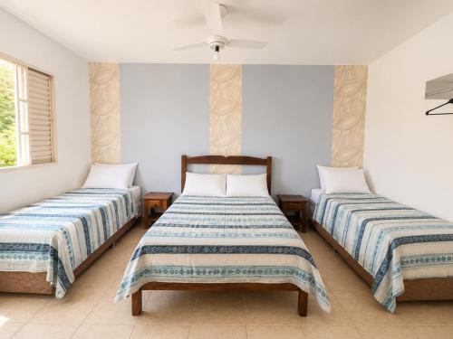 two beds in a room with white walls at Pousada Mais Cacau in Itu